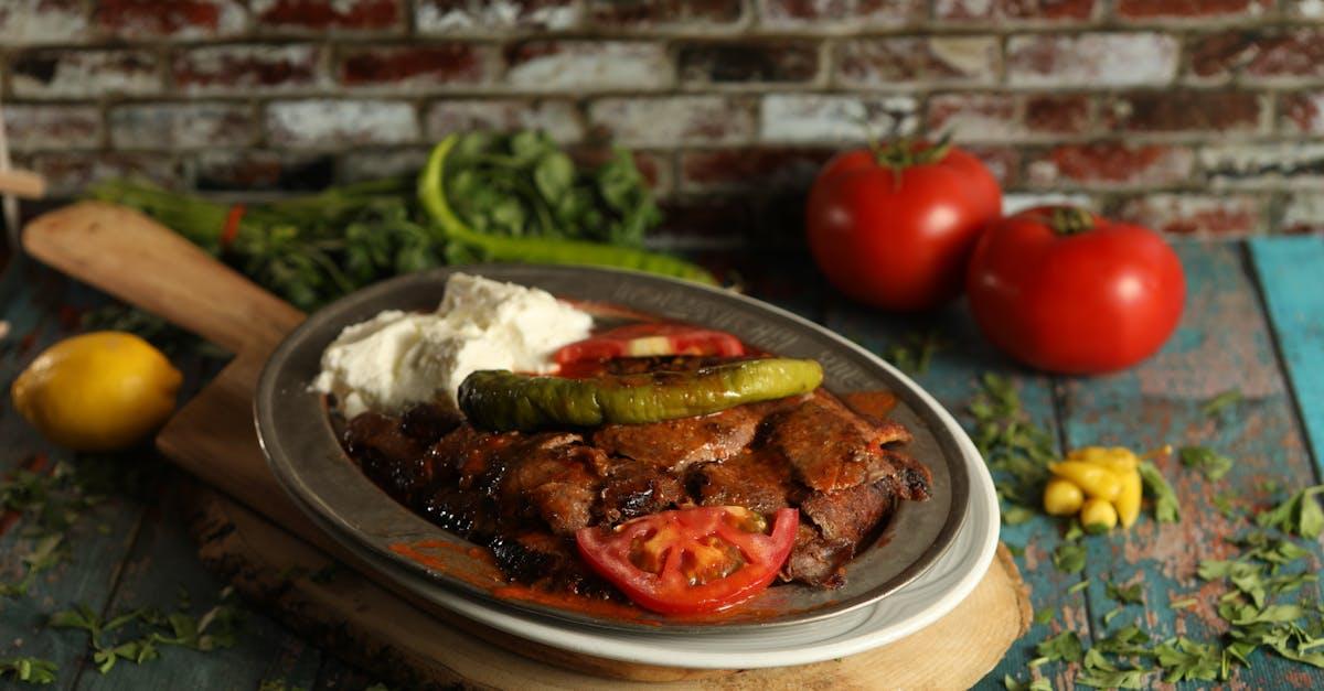 découvrez le plat traditionnel turc iskender, une délicieuse combinaison de viande d'agneau grillée, servie sur du pain pita, nappée de sauce tomate et accompagnée de yaourt crémeux. parfait pour les amateurs de saveurs authentiques.